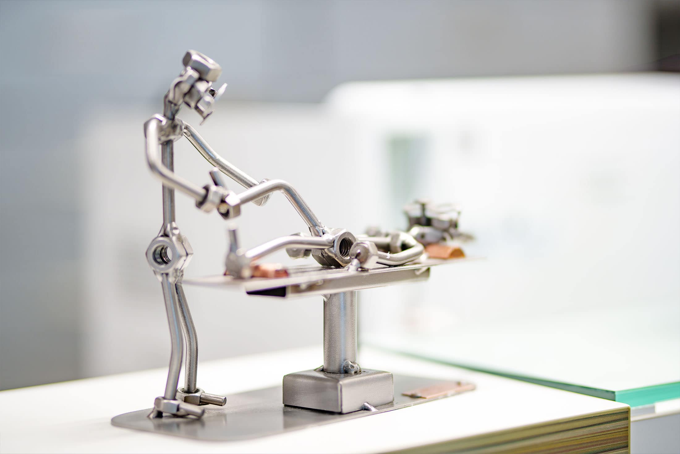 Kleine Metallfigur in liegender Haltung auf einer Behandlungsliege als Deko-Objekt